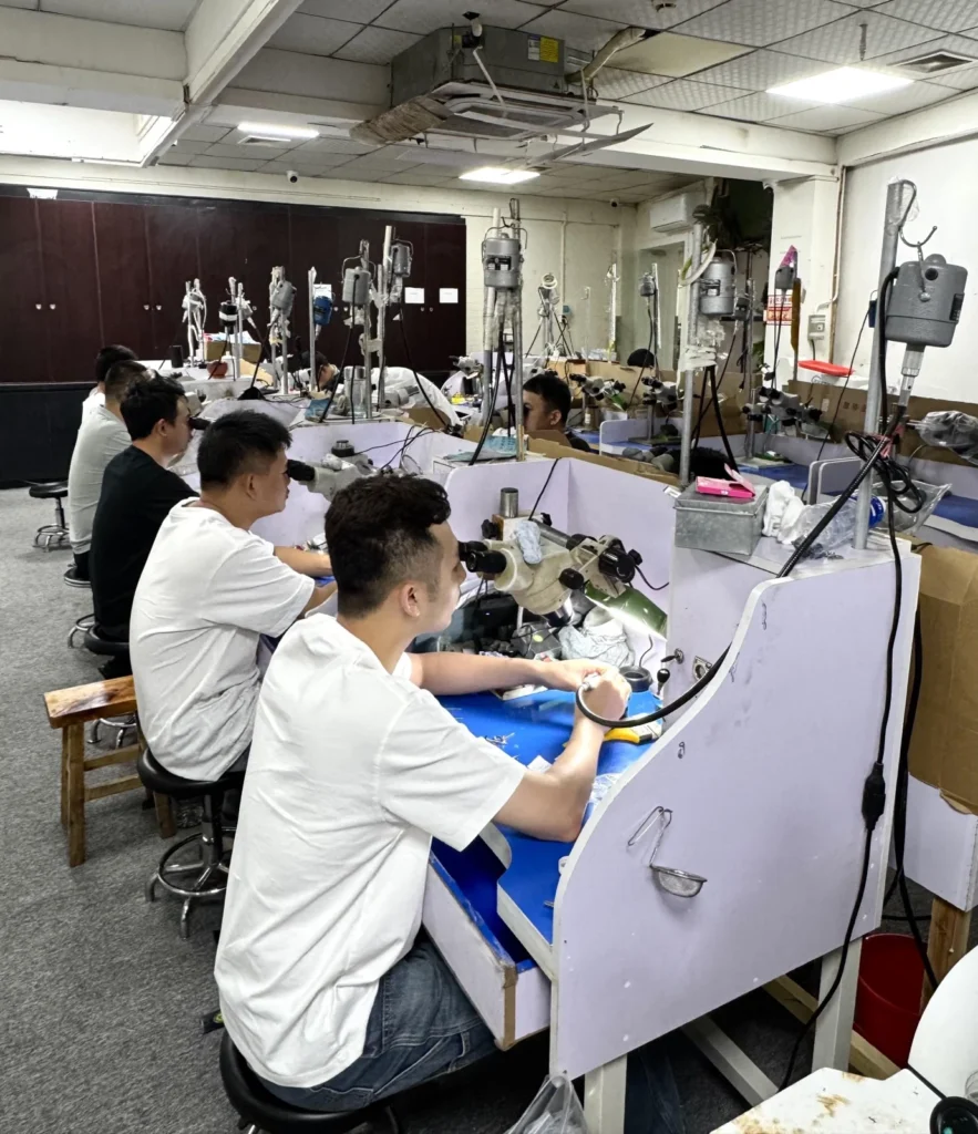 Jewelry makers working at a row of benches.